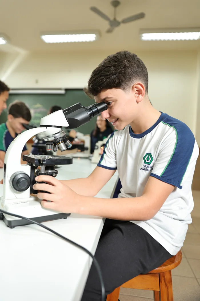 Aluno do Colégio Universitário observando lâmina no microscópio