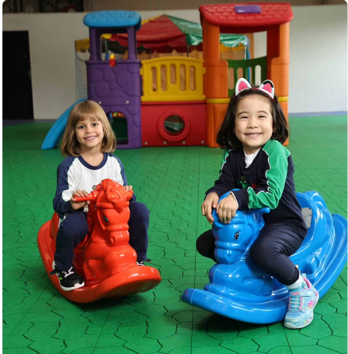 Duas alunas do Colégio Universitário brincando em brinquedos de montar em formato de cavalinho